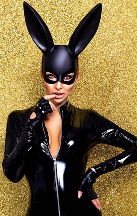 Womean wearing black latex with bunny ears against a gold background